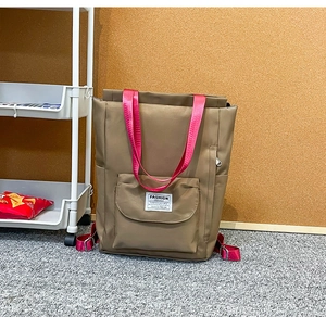 Détail du sac à dos en nylon kaki avec bretelles roses et étiquette tissée tendance