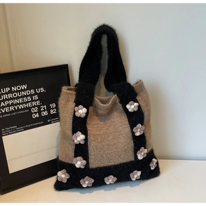 Detail of knitted tote bag featuring black feather yarn trim and 3D crochet flower accents