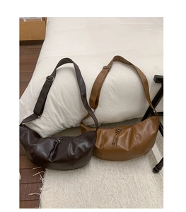 Close-up of crescent hobo bags in dark brown and caramel with tassels and wide straps