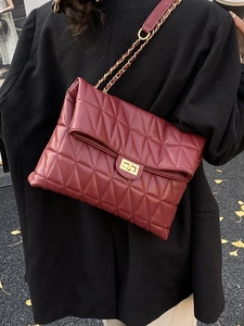 Sac bandoulière bordeaux matelassé avec chaîne dorée porté par un mannequin