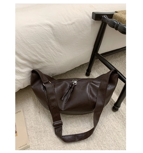 Detailed macro view of dark brown crescent bag showing fine leather texture and tassels