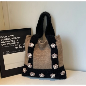 Close-up of knit tote bag with 3D crochet flowers and contrasting black handle