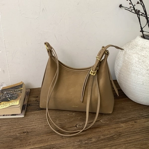 Macro view of brown leather shoulder bag detail with gold buckle and brand logo