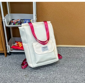 Détail du sac à dos blanc pour ordinateur avec bretelles roses et poche à rabat