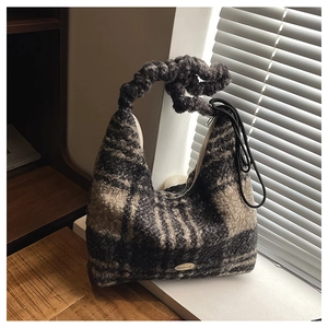 Macro shot of plaid knit tote bag with thick woven handle and metal logo detail