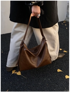 Λεπτομέρεια vintage σκούρα καφέ τσάντα tote από δέρμα κρατημένη από μοντέλο