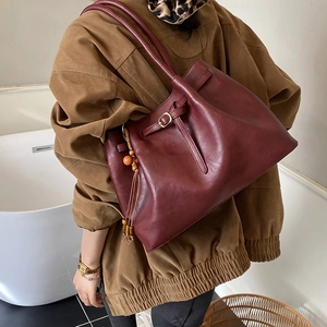 Détail du sac fourre-tout en similicuir bordeaux avec gland en bois et boucle de sangle