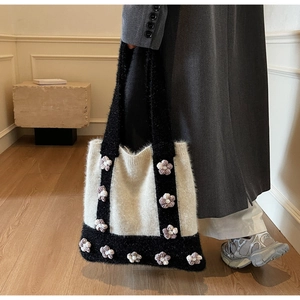 Detail of knit tote bag featuring 3D crochet flowers and soft plush texture