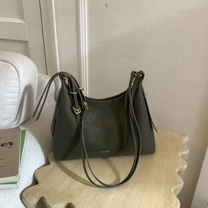 Detail of dark green leather hobo bag with gold CLEAR K logo on a wooden stool