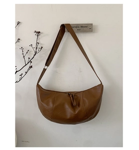 Minimalist brown crescent leather shoulder bag hanging on a modern wall hook decor