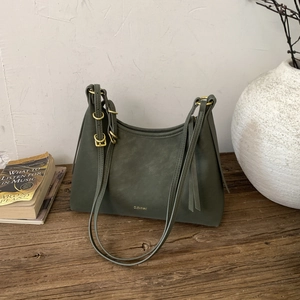Close-up of matte dark green leather bag with gold buckle and embossed brand logo