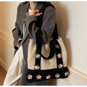 Detailed close-up of knitted tote bag showing handmade 3D flowers and soft yarn texture
