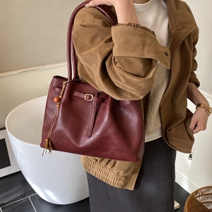 Détail du sac cabas vintage bordeaux avec breloque en bois porté à l'épaule