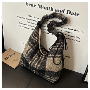 Detail of checkered sherpa tote bag with twisted shoulder strap and gold brand logo