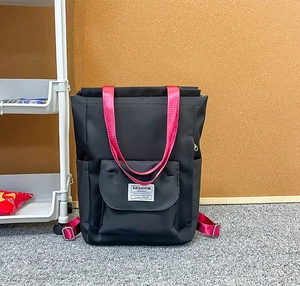 Détail du sac à dos en nylon noir avec bretelles roses et patch logo Fashion Instinct