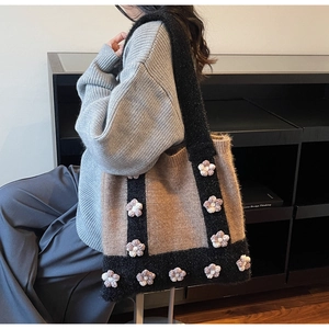 Detail of knitted tote bag showing brown and black patchwork with 3D floral accents