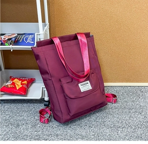 Détail d'un sac à dos en nylon bordeaux avec poche frontale et sangles résistantes