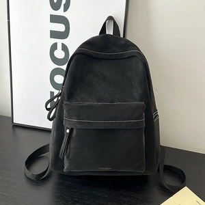 Detail of gray suede backpack showing white contrast stitching and gold lettering