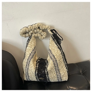 Detail of striped faux fur tote bag with textured ruffles on a black leather sofa