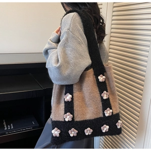 Detail of brown knitted tote bag featuring 3D crochet flowers and thick texture strap