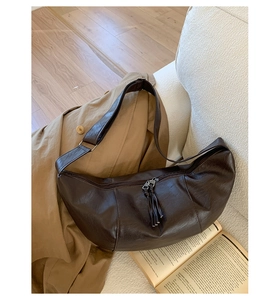 Detail view of dark brown crescent bag with smooth PU leather and tassel zipper detail