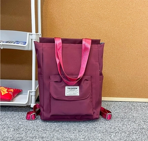 Détail du sac à dos en nylon bordeaux avec poignées roses et étiquette Fashion Instinct