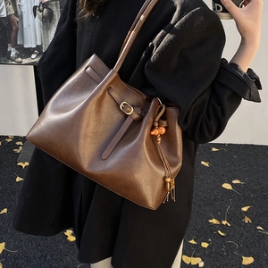 Détail du sac cabas marron vintage avec glands en perles de bois et boucles métalliques