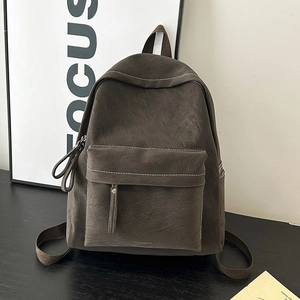 Detail view of dark brown vintage backpack with white stitching and brand logo