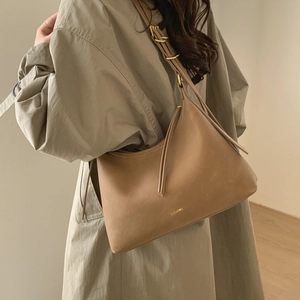 Close-up of brown leather shoulder bag with adjustable strap and gold metal hardware