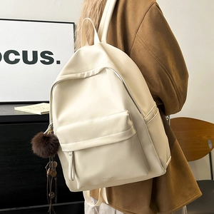 Side view of cream PU leather backpack with decorative brown pompom on a female model
