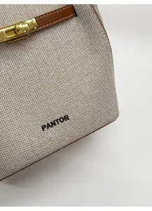 Detail of woven fabric texture with leather straps and gold metal twist lock closure
