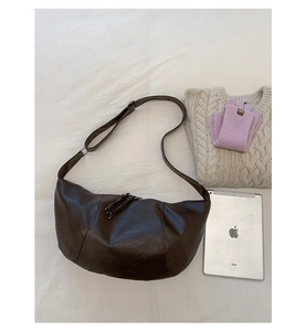 Dettaglio borsa a mezzaluna in pelle PU marrone scuro su sfondo in tessuto bianco