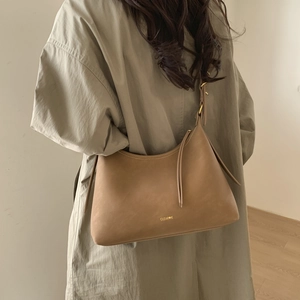 Brown suede hobo bag with long tassel detail and gold logo shown on model shoulder