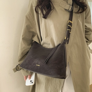 Detail of adjustable strap buckle and soft suede texture on a brown shoulder bag