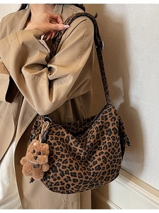Sac hobo en toile léopard avec breloque ours porté sur un trench-coat élégant et chic