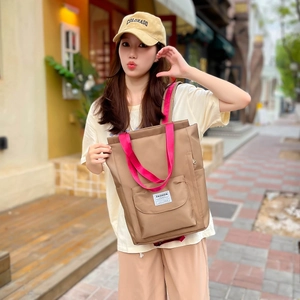 Photo en extérieur du sac cabas en nylon imperméable avec poignées rose vif contrastées