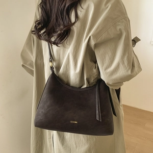 Detail of dark brown suede hobo bag with gold logo and stylish tassel accent