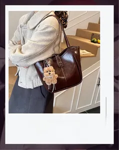 Detail of vintage dark brown faux leather bucket bag with cute plush bear pendant accessory