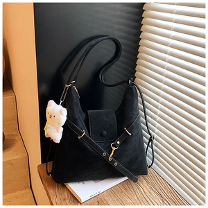 Detail of black faux leather tote with cross straps, buckle, and white bear charm decoration