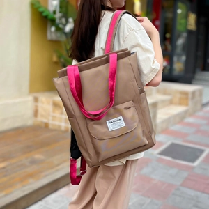 Sac cabas en nylon imperméable beige et rose porté par un mannequin en extérieur