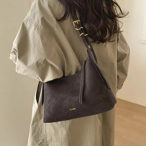 Detail of adjustable shoulder strap and gold-tone metal buckle on dark brown leather bag