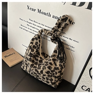 Detail of leopard print faux fur shoulder bag with ruched handle and metal logo plaque