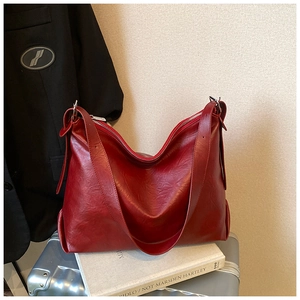 Λεπτομέρεια της vintage βαθύ κόκκινο tote τσάντας με φαρδύ λουράκι σε φόντο αποσκευών
