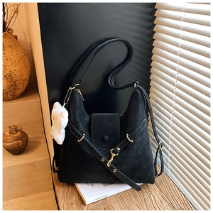 Detail view of black vintage PU leather tote bag with gold hardware and plush bear charm