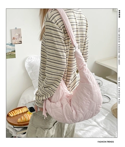 Detail of pink quilted crescent bag with heart embossed texture shown on model