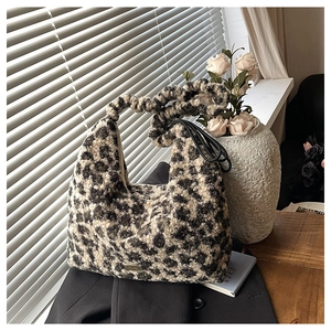 Detail of leopard print plush handbag with twisted handle and metal logo on soft fabric