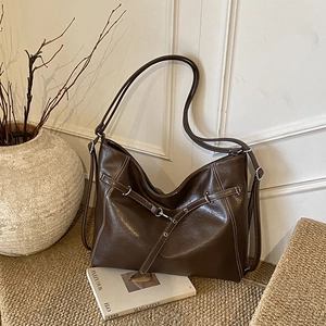 Nahaufnahme einer dunkelbraunen Shopper-Tasche aus glänzendem Leder mit Silberbeschlägen