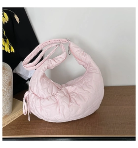 Detail of pink heart-quilted puffer bag with drawstring knots and a matching wide strap