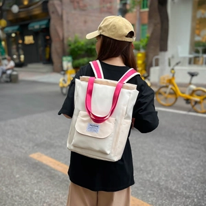 Détail du sac à dos en toile blanche avec bretelles roses et étiquette tendance