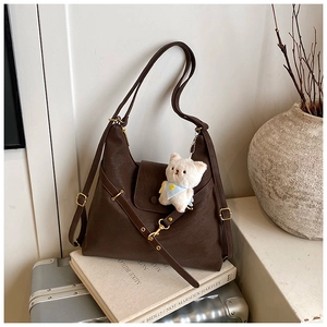 Close-up of dark brown leather tote bag with gold hardware and a cute cat charm